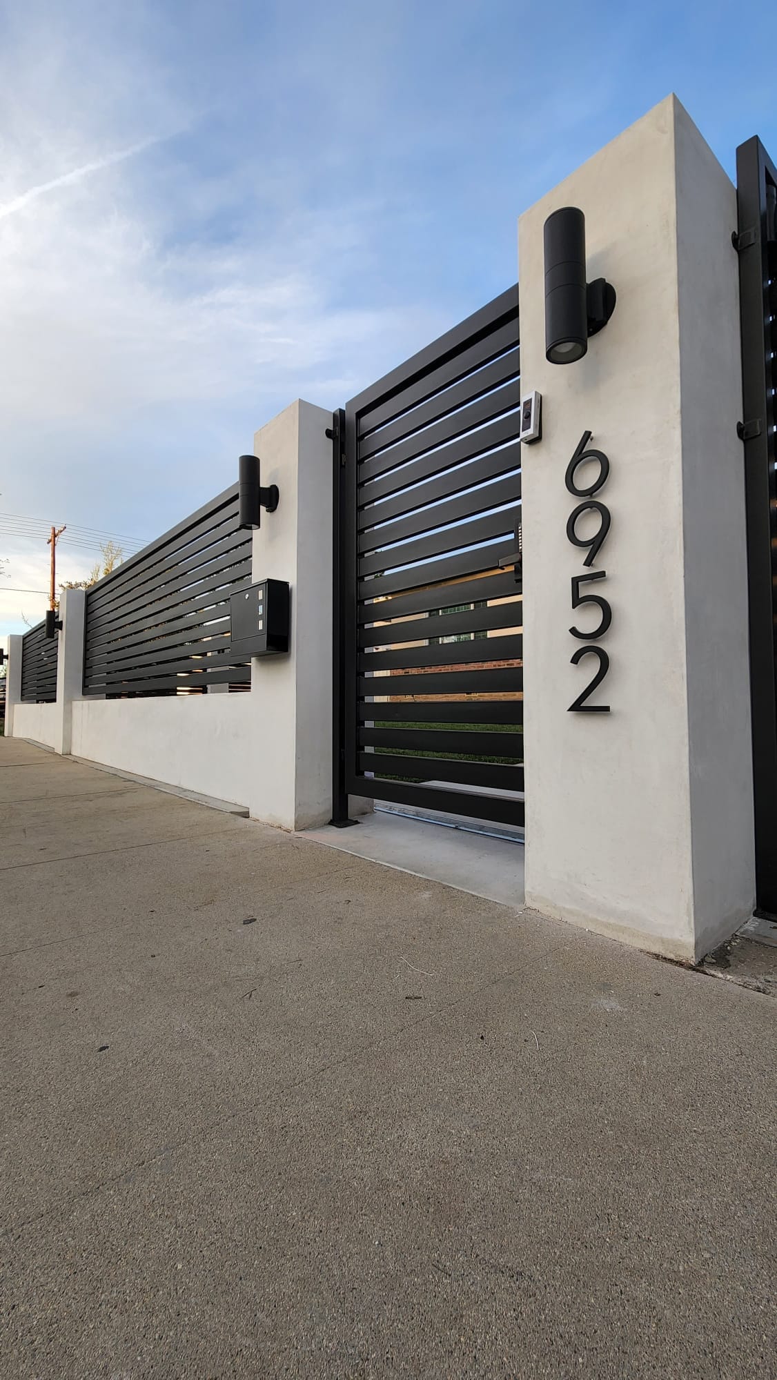 Lake Balboa. Complete project — columns, lighting, intercom system, driveway gate with vertical slats, pedestrian gate, and horizontal-design metal fence.