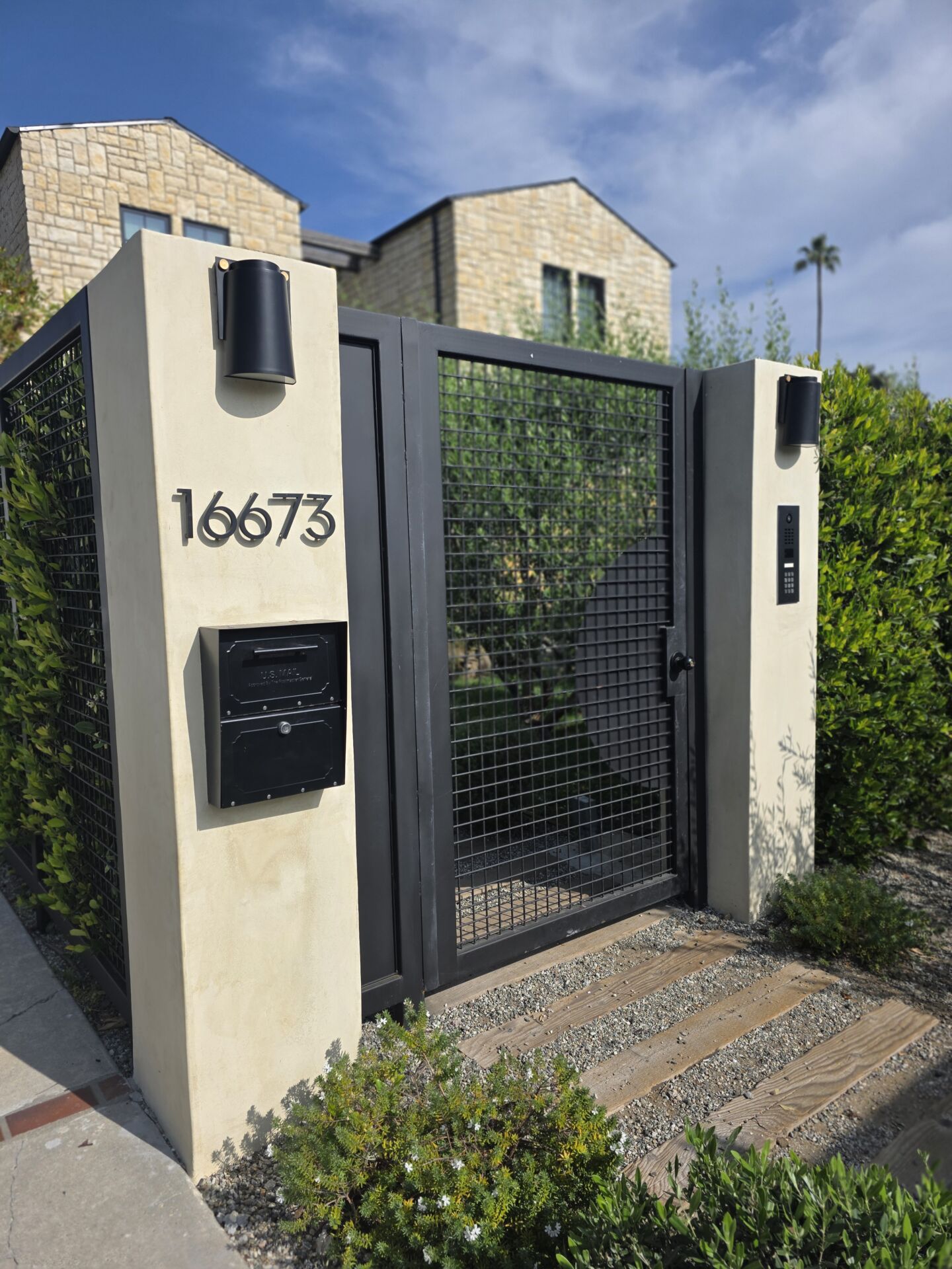 All-metal pedestrian gate with fixed panel and square mesh, DoorBird intercom, built-in mailbox, two smooth-stucco columns with lights on top. Sherman Oaks.