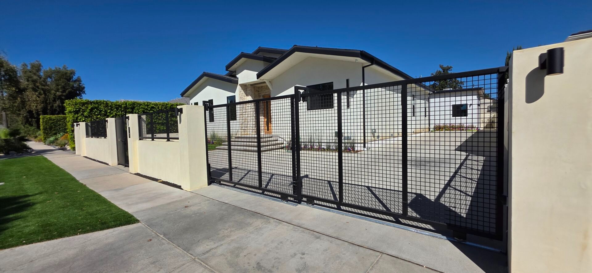 Square-mesh tandem sliding gate set in a stucco block wall with columns at a Reseda residence