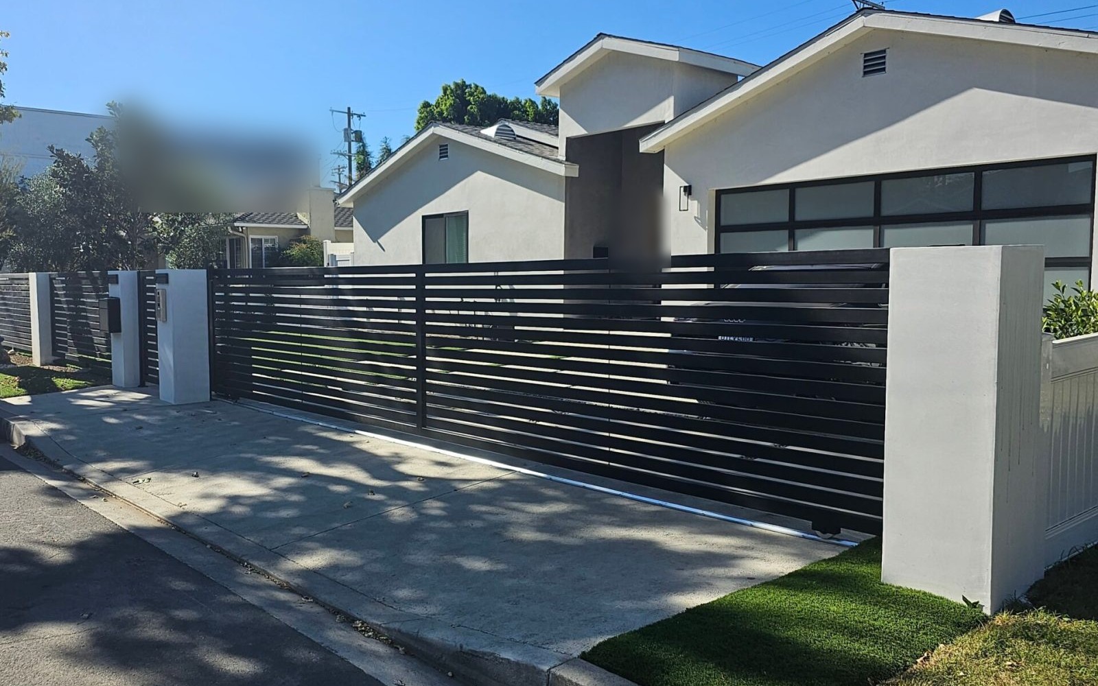 Horizontal-slot sliding driveway gate with full-view garage door, matching pedestrian gate and slat fencing at a Sherman Oaks residence