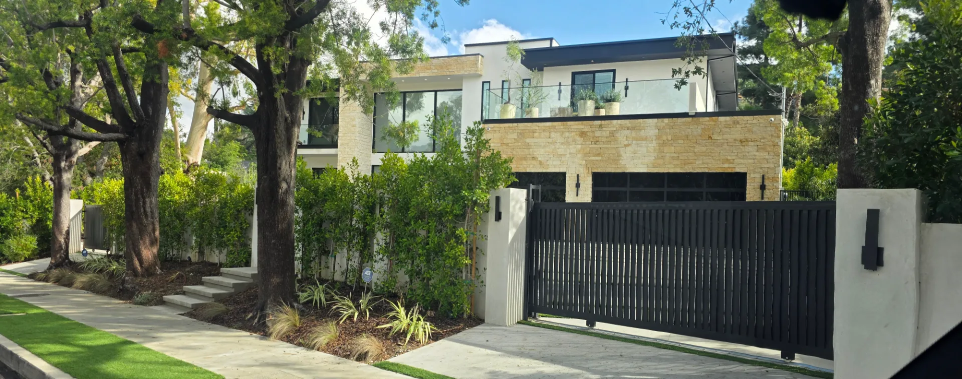Encino. Vertical-slat gate with columns, black-frame black-glass garage door, intercom system, All-O-Matic gate motor.