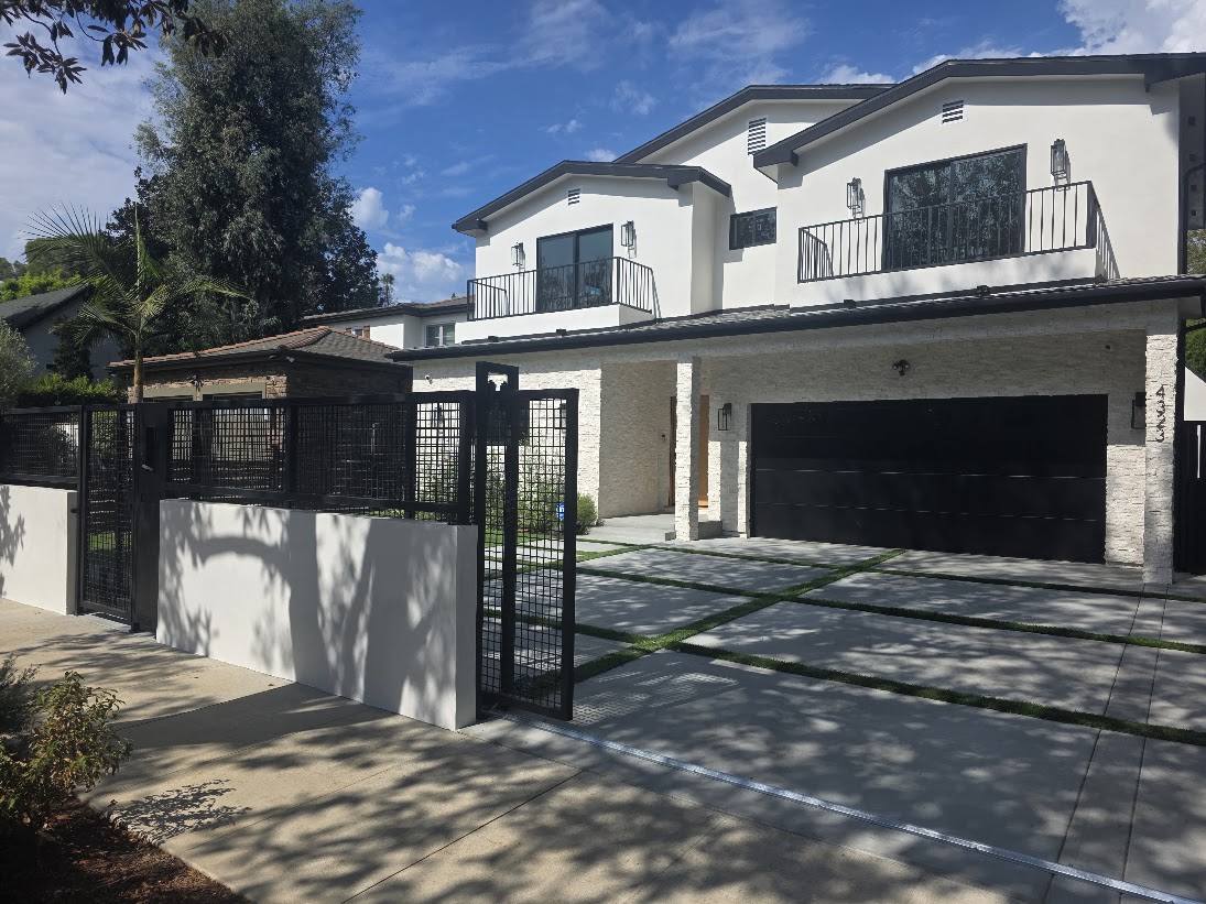 White two-story home with a new black flush garage door, driveway gate, fencing and concrete driveway