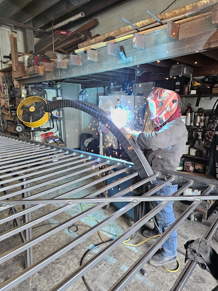 Technician welding a new steel gate frame on the bench in the Silence fabrication shop